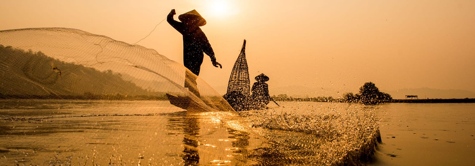 Traditional fishermen throwing nets by hand from a small boat